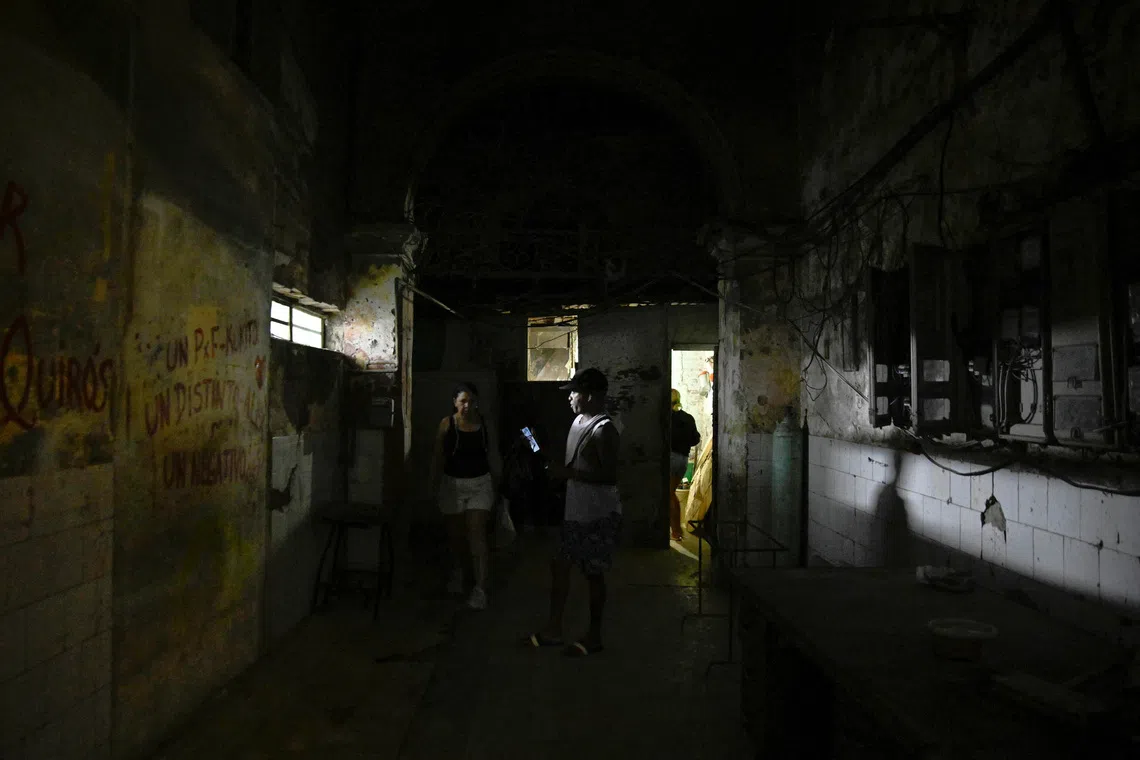 People walk through a hallway after power was restored following a partial collapse of the electrical grid that left much of western Cuba in the dark, in Havana, Cuba, December 3, 2025. REUTERS/Norlys Perez