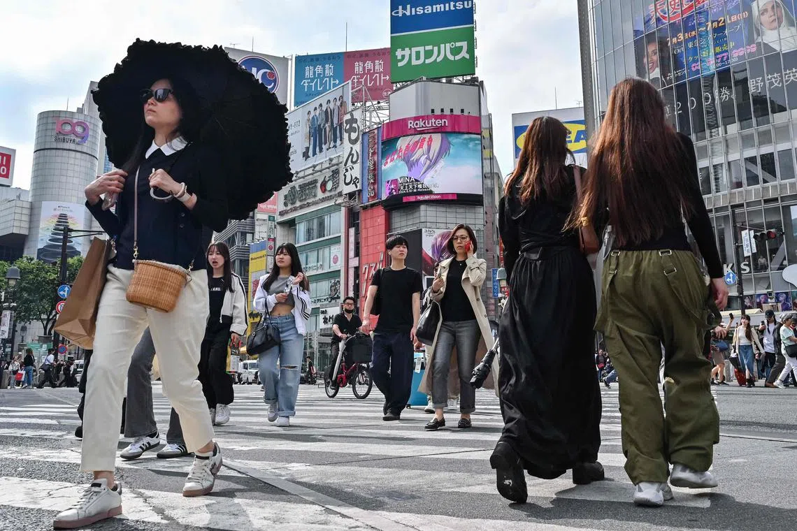 Pedestrians cross the intersection at Shibuya Crossing in the Shibuya district of Tokyo on May 20, 2024. (Photo by Richard A. Brooks / AFP)