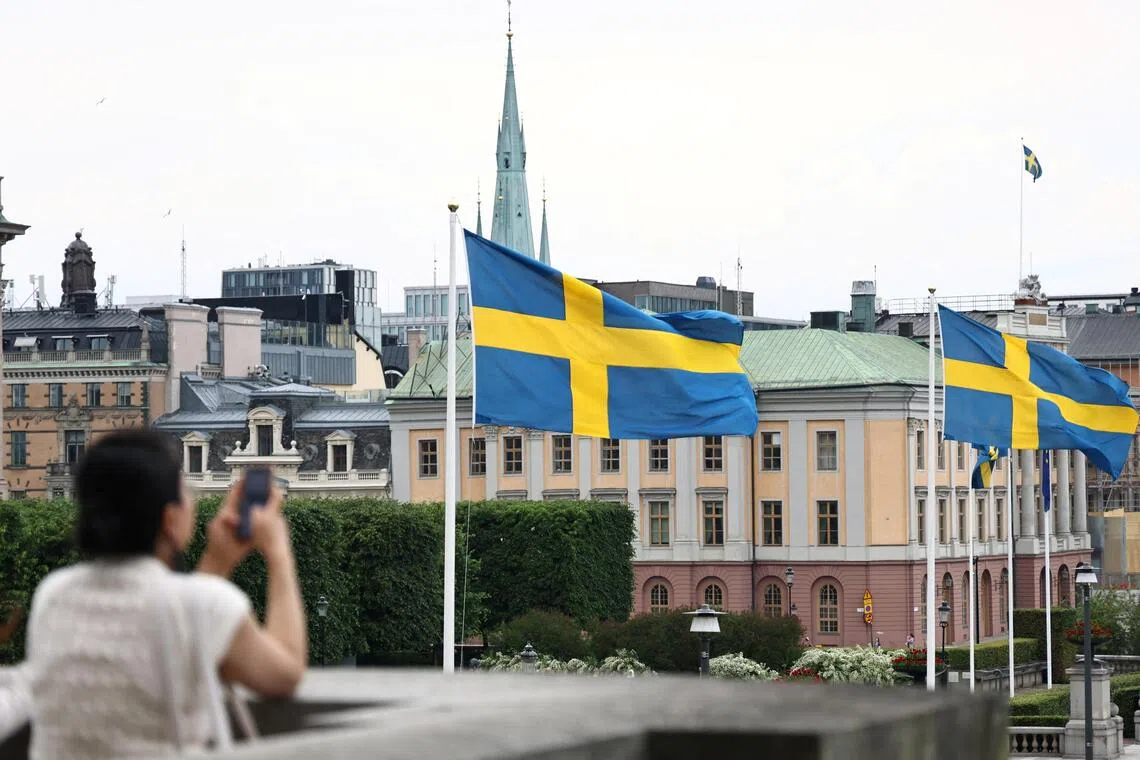Person taking a photo of a building with Swedish flags in front of it.