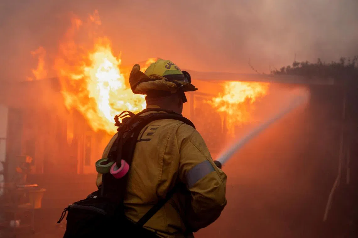A firefighter works to extinguish the fire as the Palisades Fire burns during a windstorm on the west side of Los Angeles, California, U.S. January 7, 2025. REUTERS/Ringo Chiu