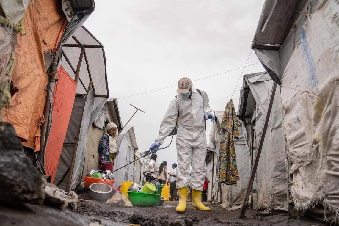 A Red Cross worker spraying chlorine, as other Red Cross personnel raise awareness about the spread of mpox and the importance of hygiene, in the Democratic Republic of Congo. 