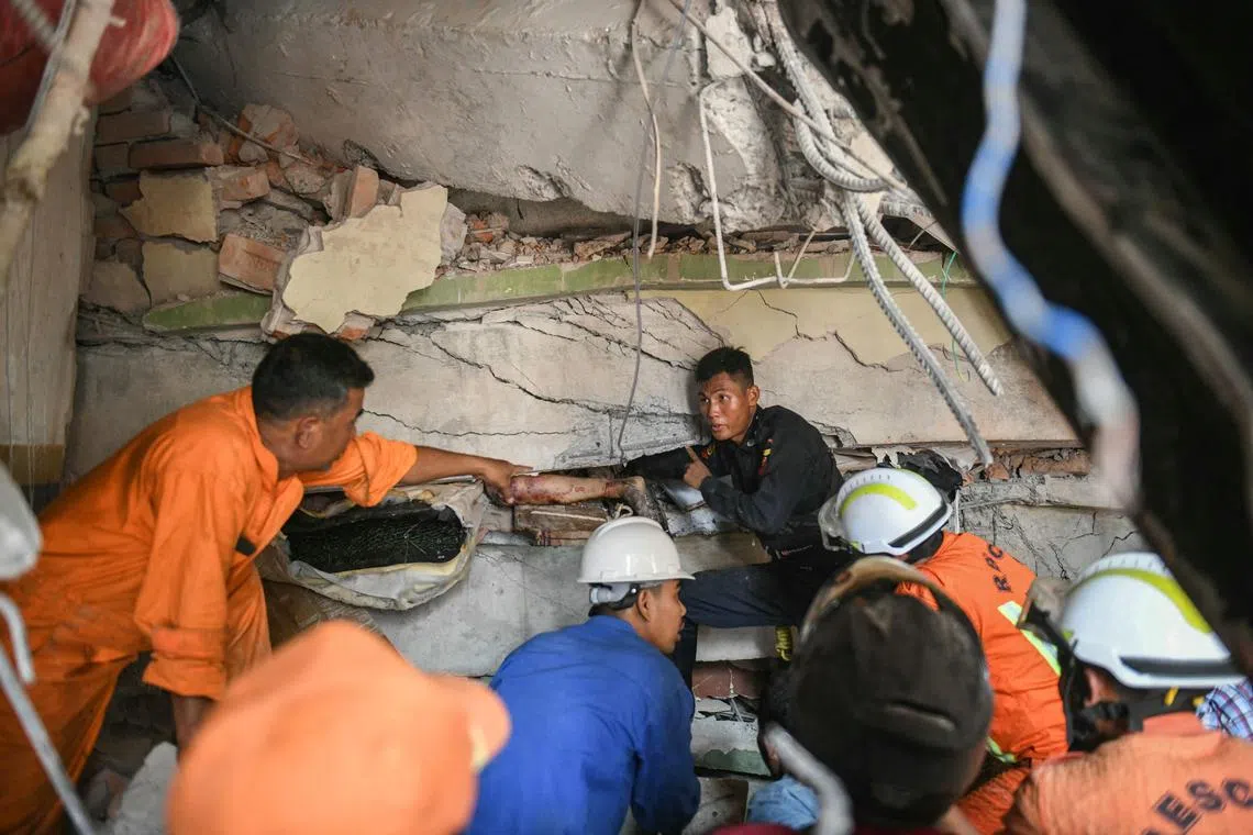 Rescue workers attempt to free a woman trapped under the rubble of a condominium in Mandalay.