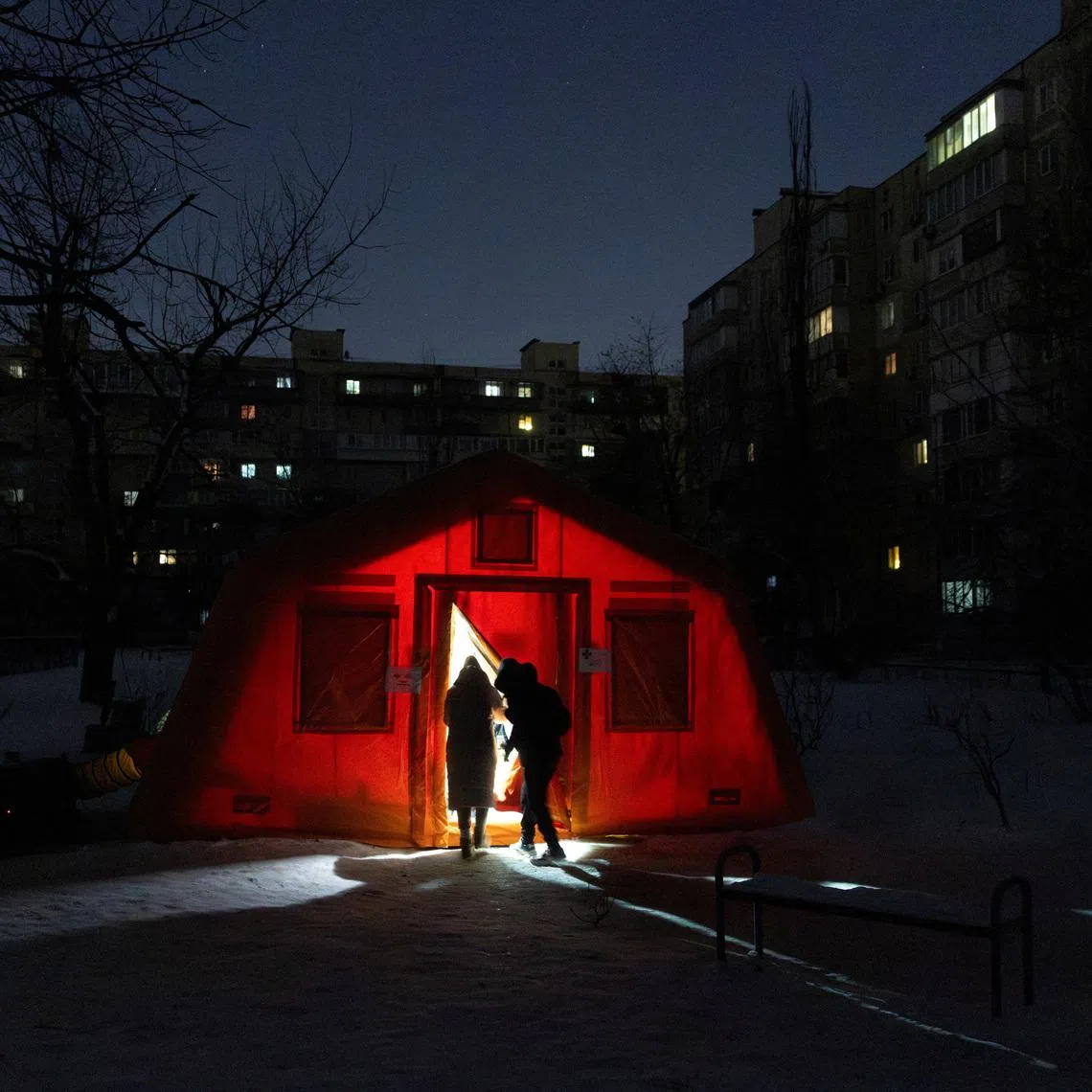 People enter a tent provided by emergency services for residents whose apartments are left without heating during sub-zero temperatures, amid Russia's attack on Ukraine, during a winter night in Kyiv, Ukraine January 17, 2026. REUTERS/Thomas Peter