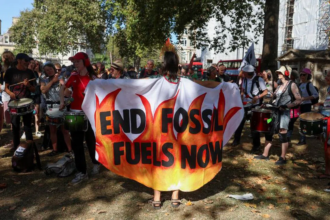 A demonstrator is draped in a piece of fabric with a slogan as activists take part in a global protest to end fossil fuels, in London, Britain, September 16, 2023. REUTERS/Susannah Ireland/File Photo