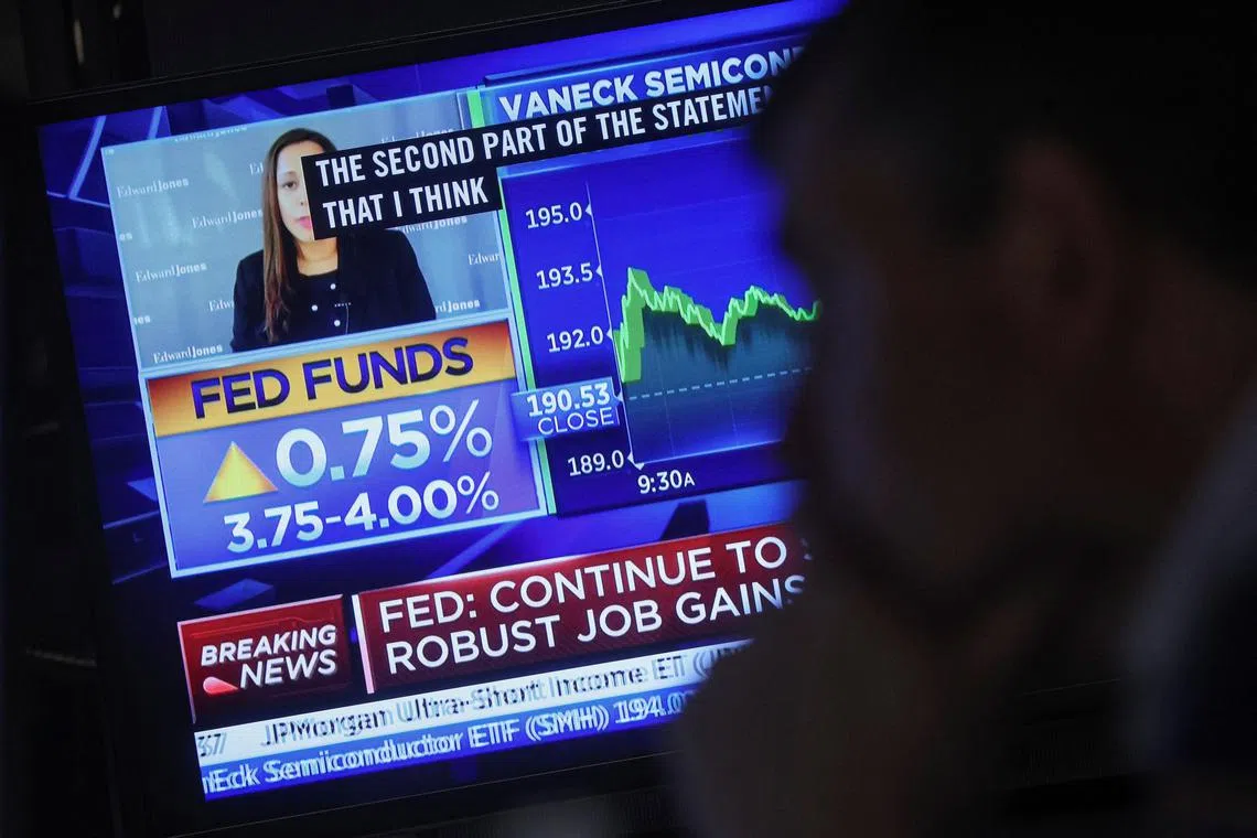 A screen displays the Fed rate announcement as a trader works on the floor of the New York Stock Exchange.