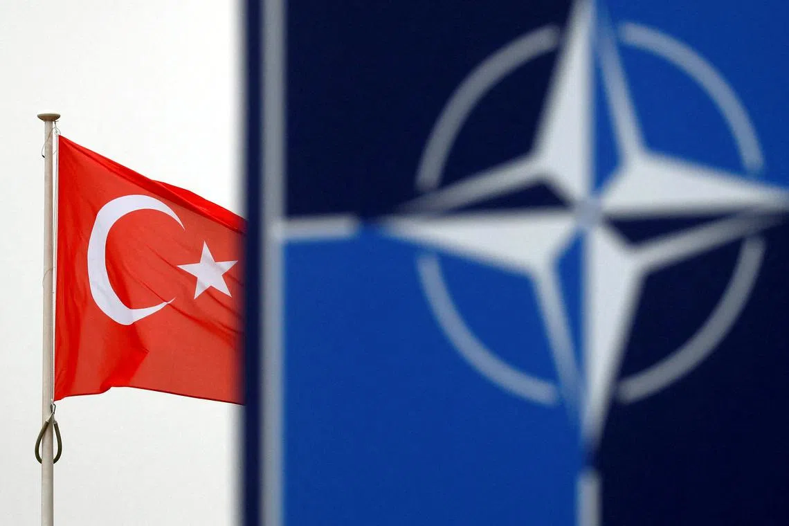 A Turkish flag flies next to the Nato logo at the Alliance's  headquarters in Brussels, Belgium.