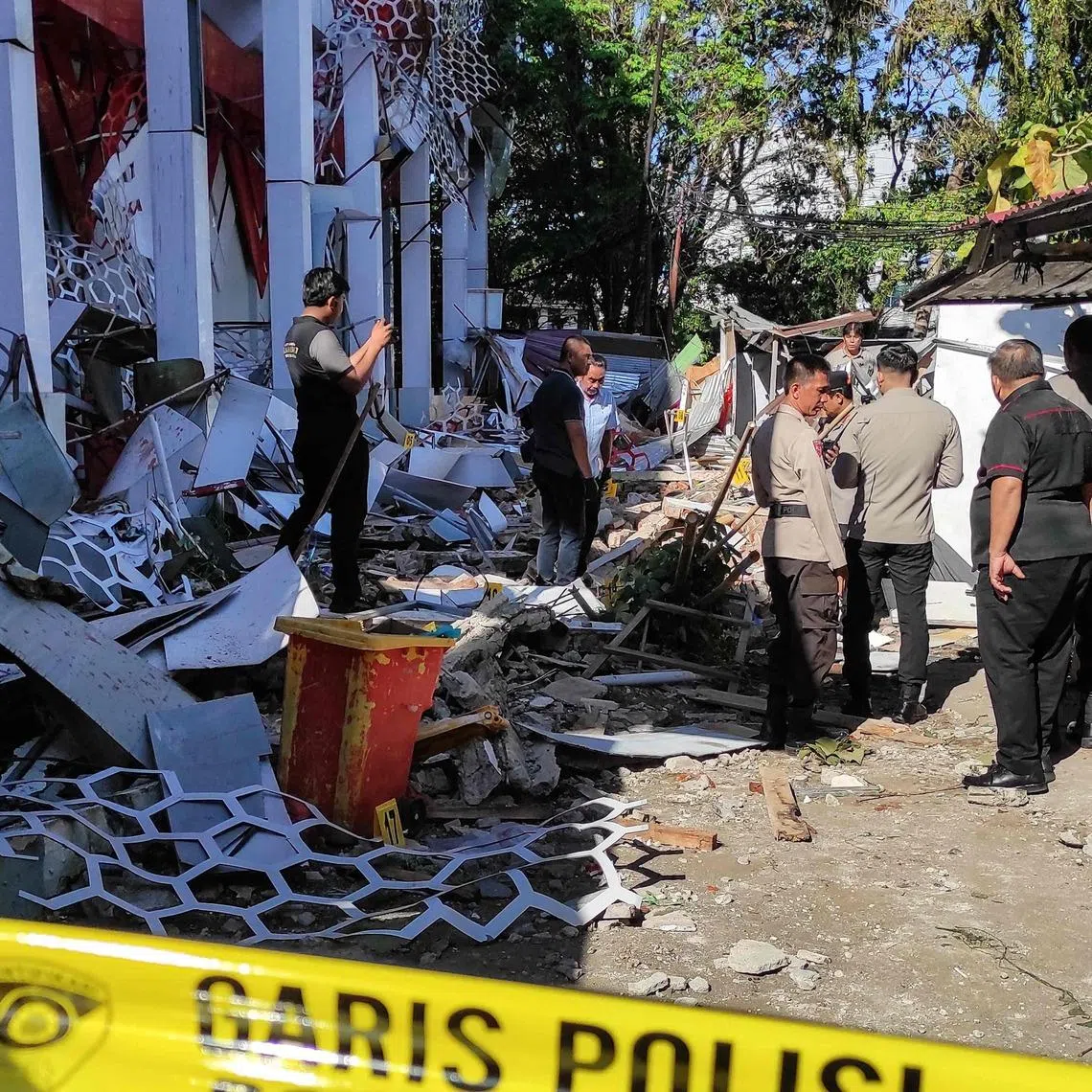 Police officers look at a damaged building following a major  7.4-magnitude offshore quake in Manado, North Sulawesi, on April 2.