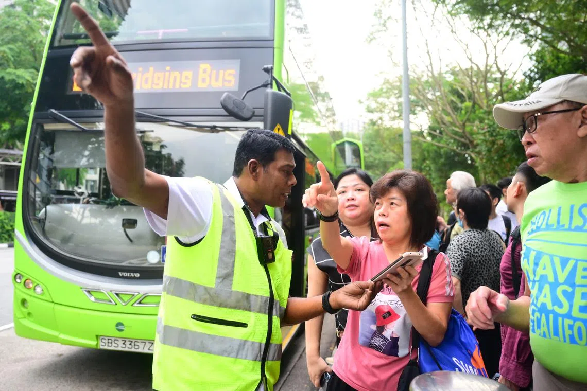 An SMRT staff helping to passengers to navigate the bus bridging services at the bus stop outside the Buona Vista MRT station, on Sept 25, 2024. 