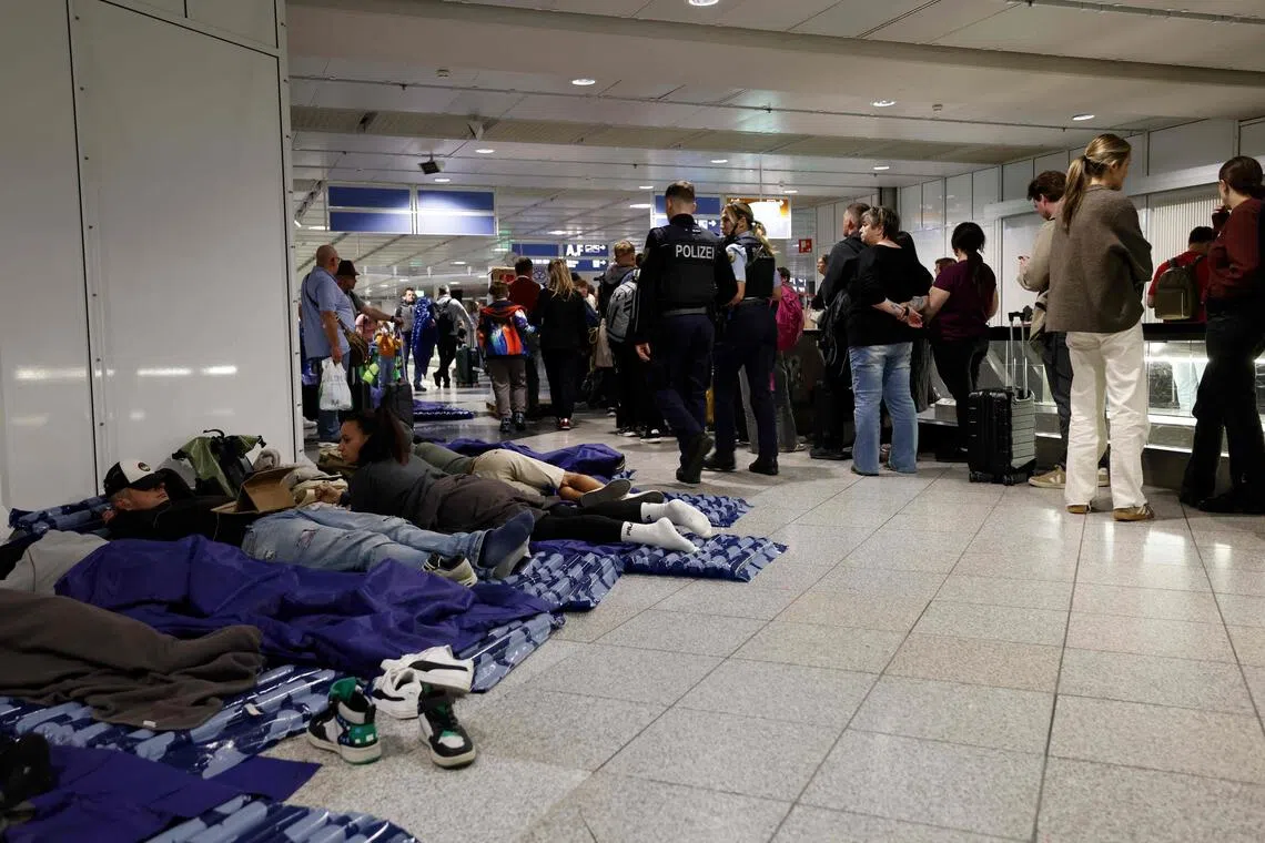 Travellers sleeping in Munich Airport early on Oct 4 after both runways were closed.