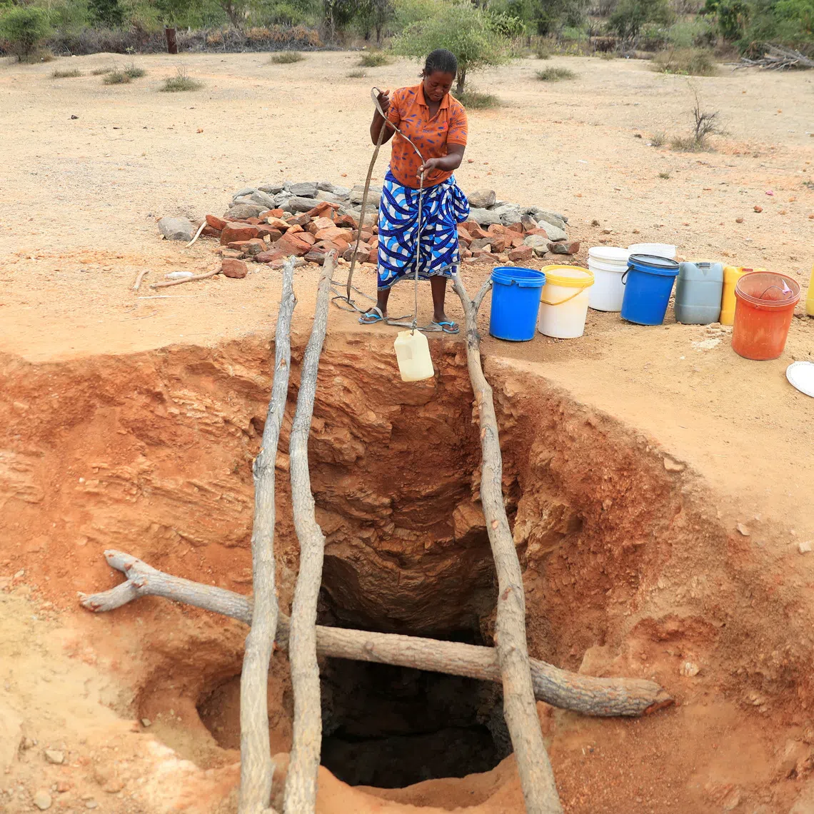 A woman fetches drinking water from an unprotected well in drought-stricken Zimbabwe.