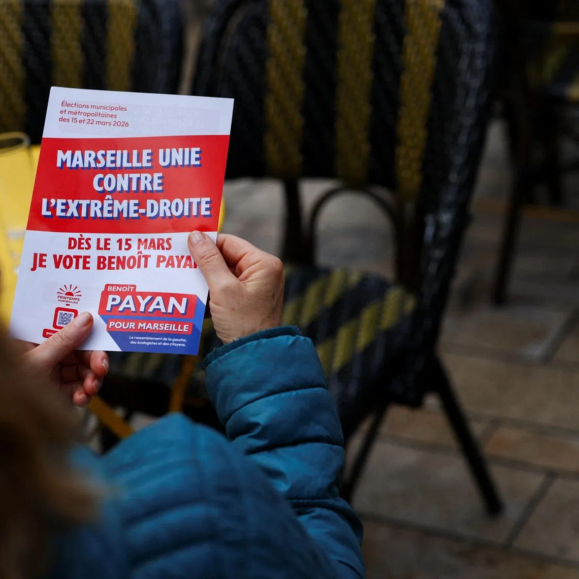 A woman holds in her hands a leaflet reading \"Marseille united against the far right\" of Marseille Mayor Benoit Payan, candidate supported by the left-wing parties for the 2026 mayoral election at the La Plaine market in Marseille, France, March 10, 2026. REUTERS/Manon Cruz