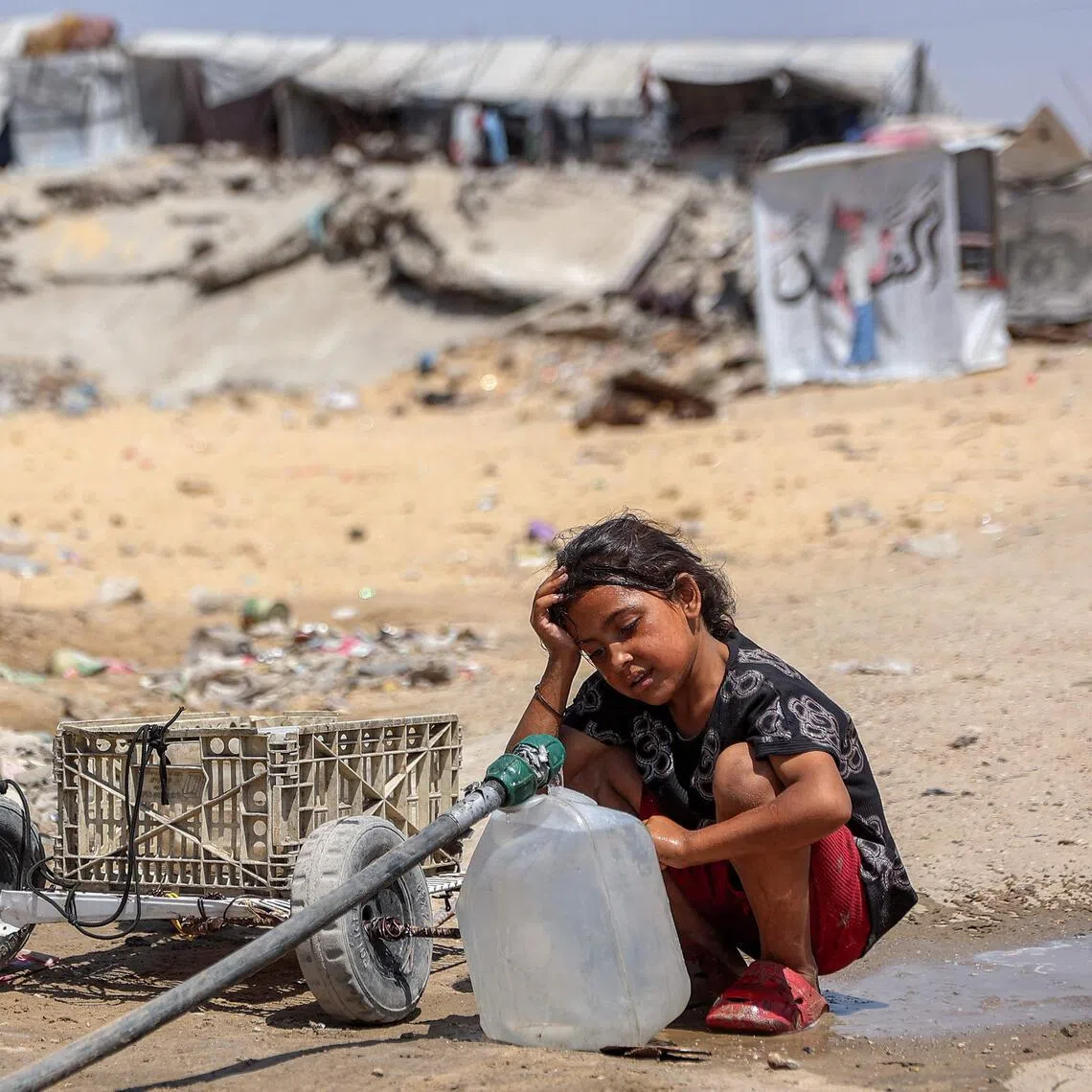A girl fills containers with water drawn from the leftovers of underground pipes at a camp for people displaced by war in Gaza City.