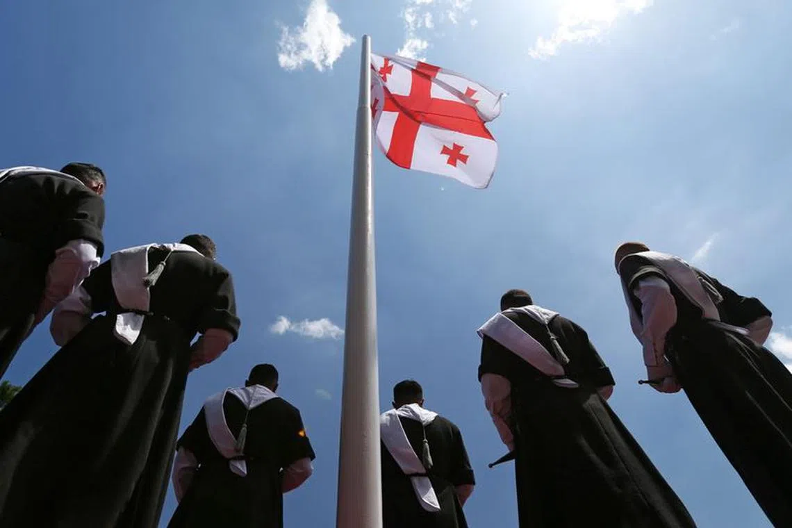 FILE PHOTO: Men wearing traditional clothes stand next to the Georgian flag during the Independence Day celebrations in Tbilisi, Georgia May 26, 2022. REUTERS/Irakli Gedenidze