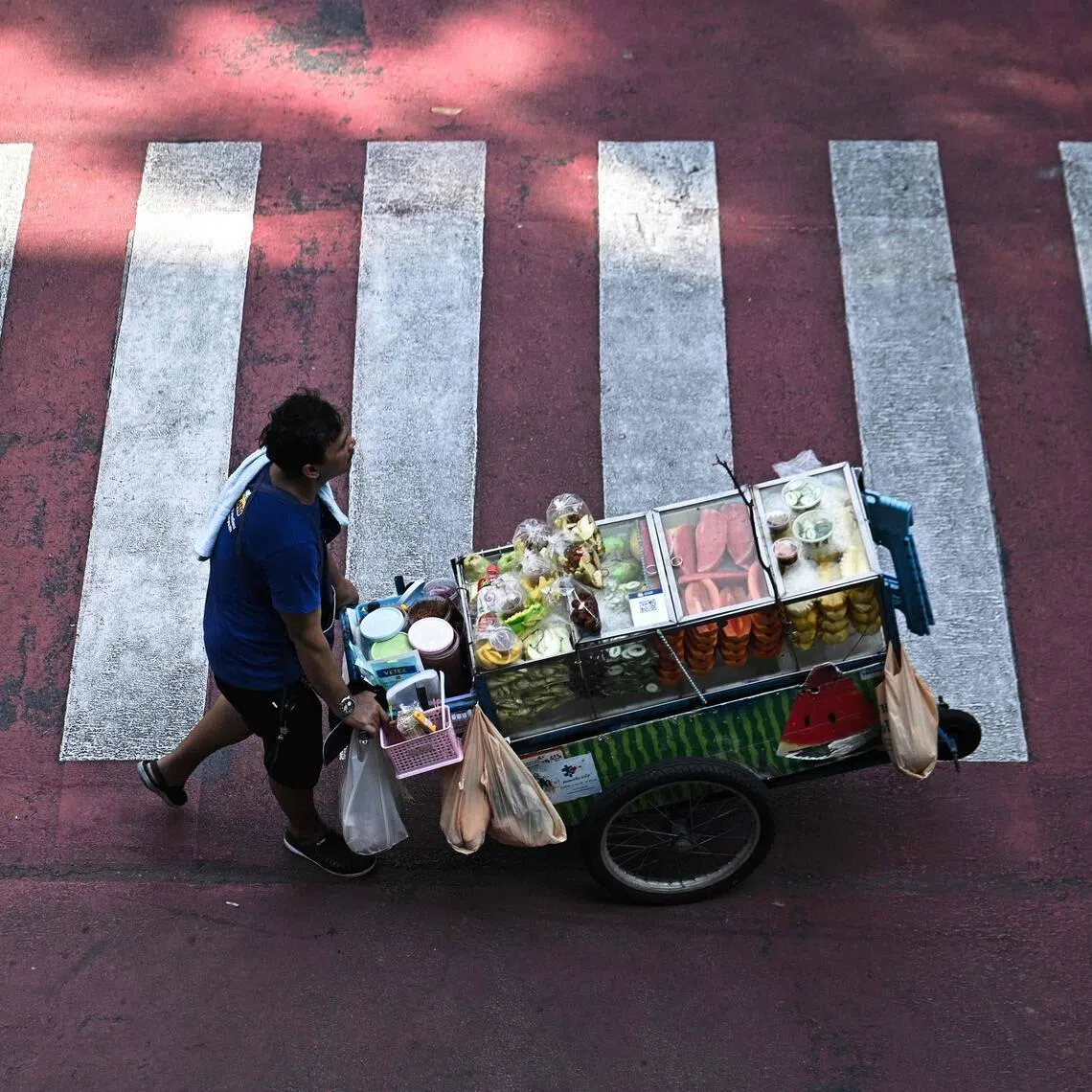 A street vendor pushes a cart of fresh fruit in Bangkok on April 30. 