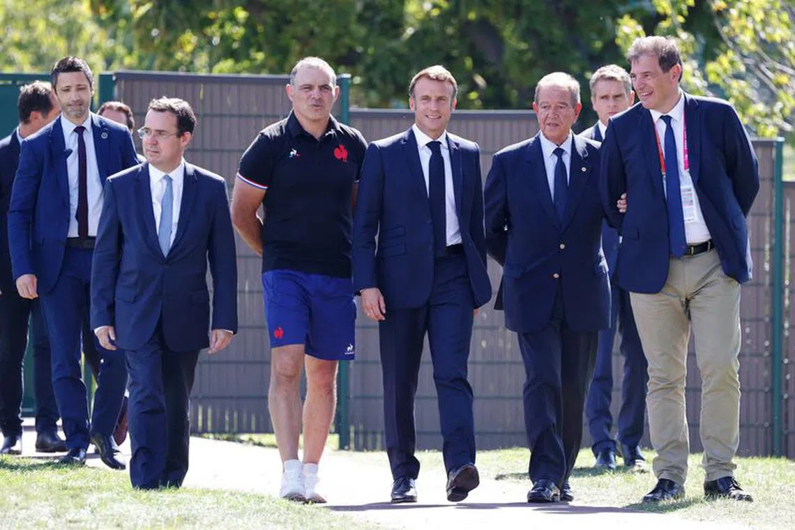 French President Emmanuel Macron walks with France's assistant coach Raphael Ibanez and Mayor of Rueil-Malmaison Patrick Ollier as he arrives for a meeting with France's rugby team at their base camp's training pitch in Rueil-Malmaison, outside Paris, France September 4, 2023. Ludovic MARIN/Pool via REUTERS
