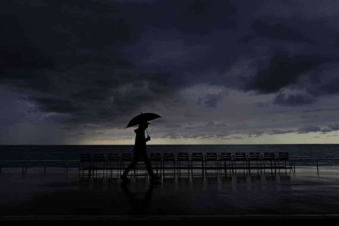 TOPSHOT - A man holds an umbrella as he on the "Promenade des anglais" on the French riviera city of Nice, on October 3, 2024. (Photo by Valery HACHE / AFP)