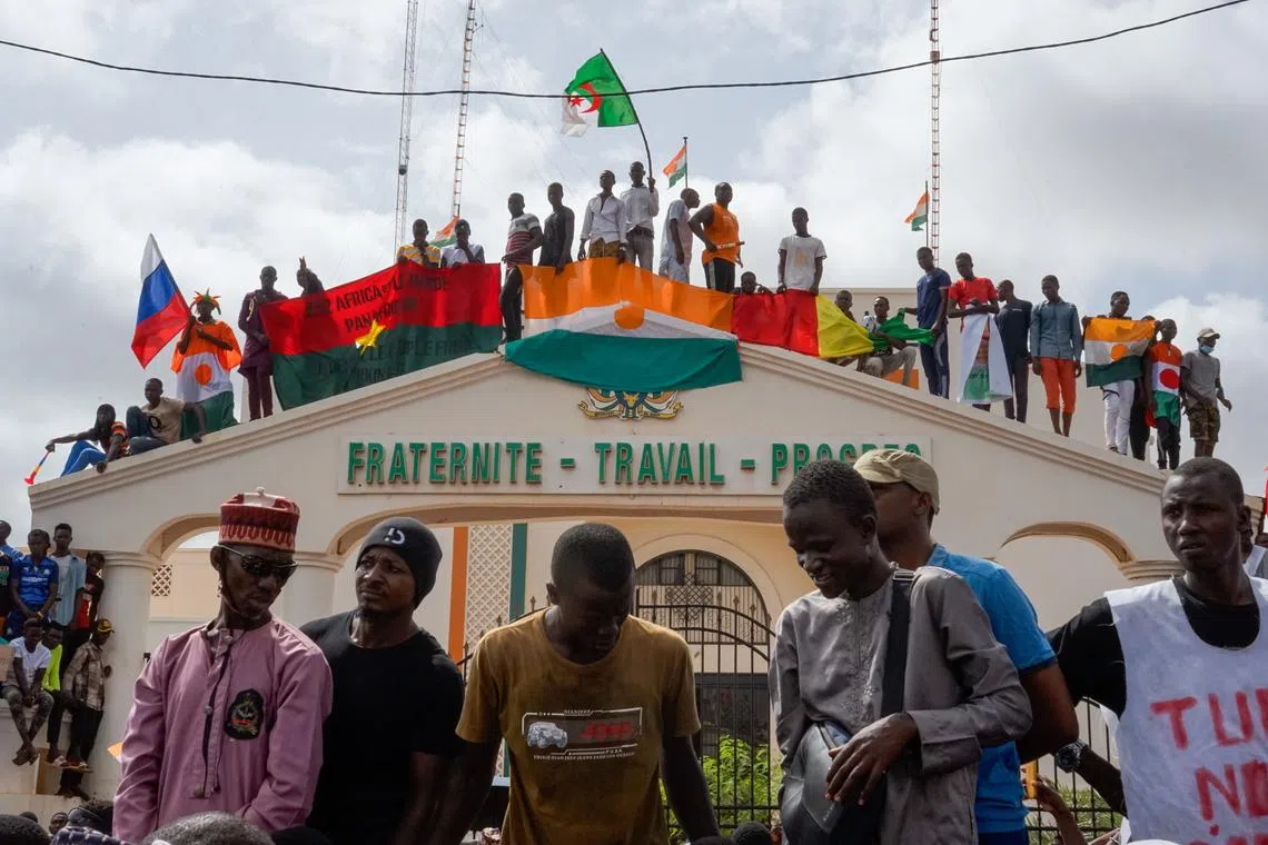 Protesters stand on top of the entrance to the National Assembly during a rally in Niamey, Niger, on Aug 3, 2023.