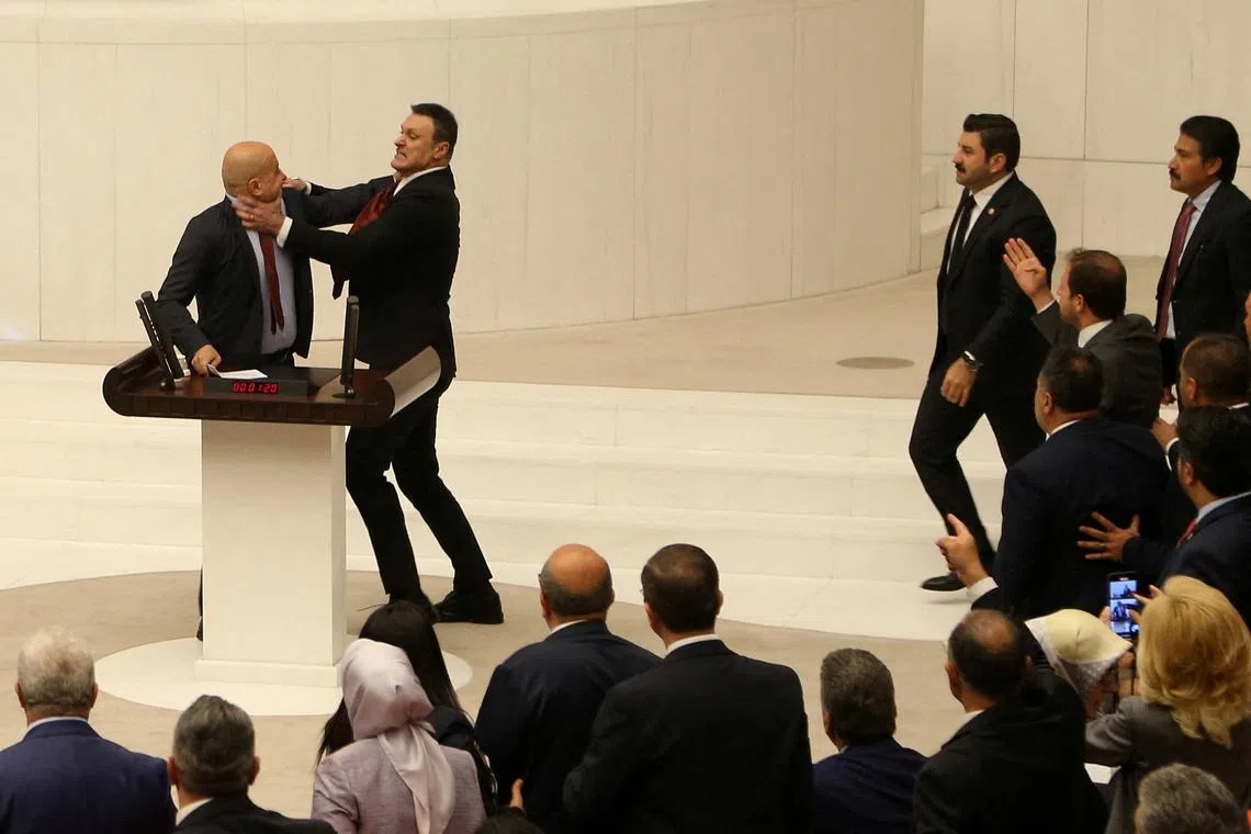 Turkey's AK Party lawmaker Alpay Ozalan scuffles with Workers' Party of Turkey (TIP) lawmaker Ahmet Sik, who was speaking during an extraordinary meeting of the Turkish parliament to discuss jailed opposition lawmaker Can Atalay's return to the assembly, in Ankara, Turkey August 16, 2024. REUTERS/Cagla Gurdogan