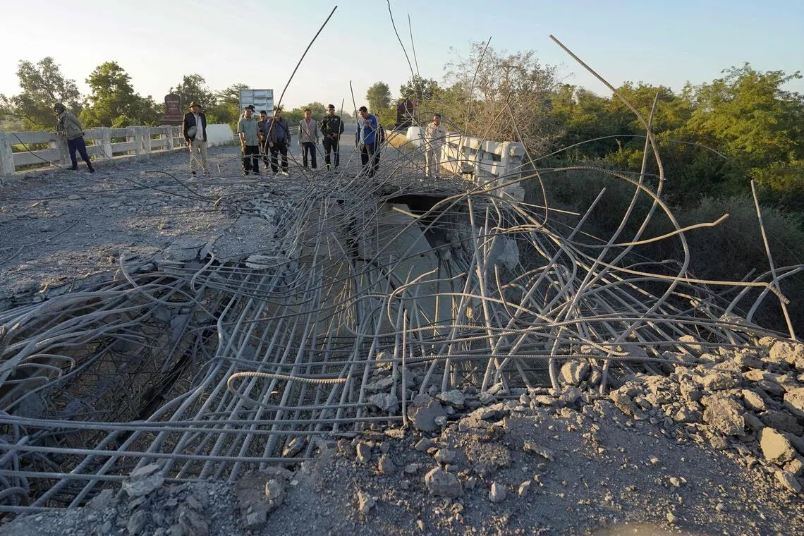 People look at a damaged bridge after Thailand carried out air strikes in an area between Cambodia's Oddar Meanchey and Siem Reap provinces on Dec 20, 2025.  