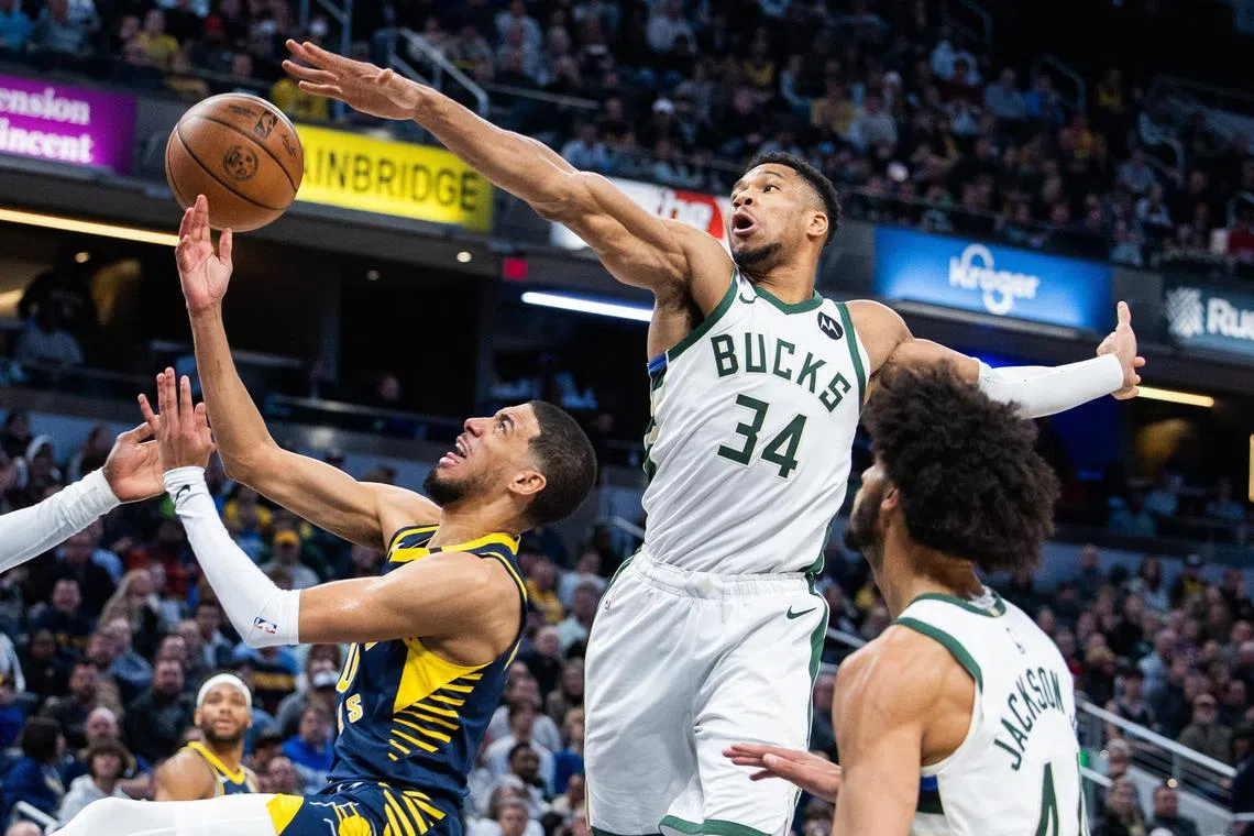 Indiana Pacers guard Tyrese Haliburton (0) attempting a shot while Milwaukee Bucks forward Giannis Antetokounmpo (34) tries to stop him.