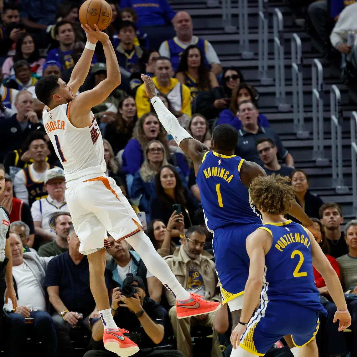 Phoenix Suns guard Devin Booker shoots a two-point basket over Golden State Warriors forward Jonathan Kuminga during the second half.