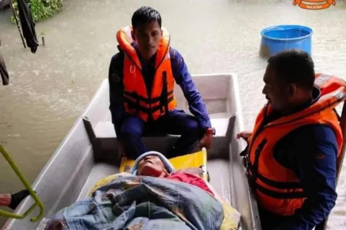 Members of Malaysia's Civil Defence Force evacuating an elderly woman from floods in Machang, Kelantan, on Dec 18, 2022.