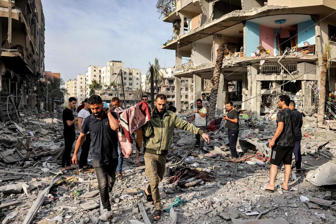 Palestinian men carrying away the body of a person killed by Israeli bombardment along a debris-littered street in al-Karama district in Gaza City on Wednesday.