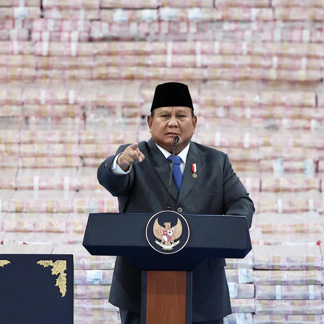 Indonesian President Prabowo Subianto gestures while delivering a speech in front of stacks of banknotes representing fines paid by companies found to have operated illegally in forest areas, during a ceremony marking the work of his forestry task force that has led to a crackdown on illegal plantations and mines, at the Indonesian Attorney General’s Office in Jakarta, Indonesia, April 10, 2026.