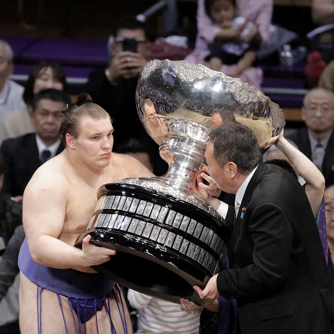 21-year-old Ukrainian sumo wrestler sekiwake Aonishiki, his real name Danylo Yavhusishyn, receives the Prime Minister's Cup from Takahiro Inoue, an advisor to Prime Minister Sanae Takaichi, after becoming the first from his nation to win a tournament of traditional Japanese sport, on the final day of the 15-day Kyushu Grand Sumo Tournament, at Fukuoka Kokusai Center in Fukuoka, southwestern Japan, November 23, 2025.   Kyodo/via REUTERS