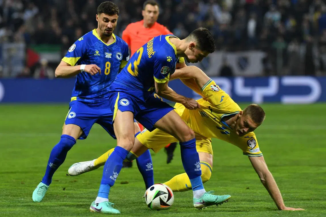 Bosnia and Herzegovina's Dennis Hadzikadunic (in blue) challenging Artem Dovbyk of Ukraine during the Euro 2024 play-off match on March 21.