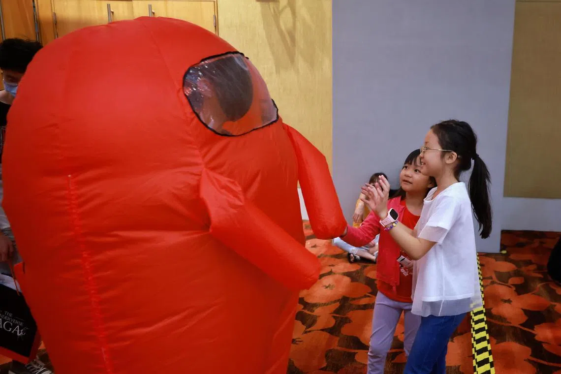 Children interacting with a cosplayer dressed as a character from the online game Among Us during Singapore Comic Con at the Sands Expo & Convention Centre on Sunday (Dec 11, 2022). 