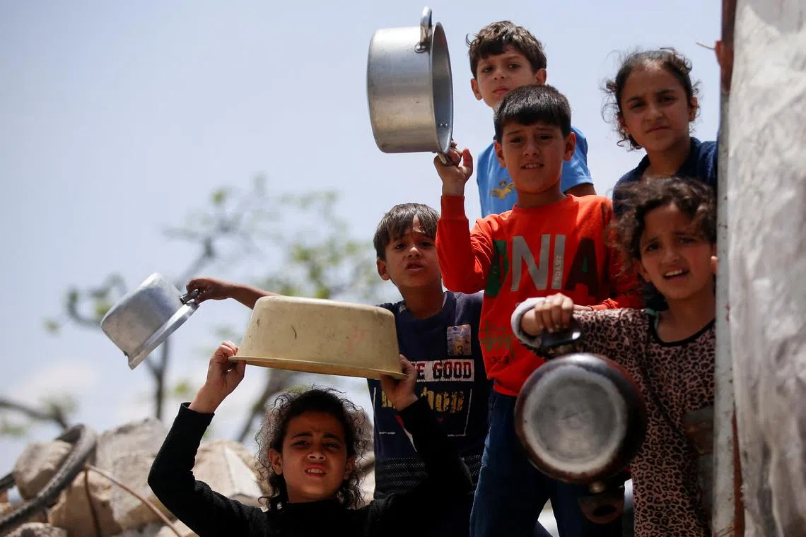 FILE PHOTO: Palestinians wait to receive food cooked by a charity kitchen, in Jabalia, in the northern Gaza Strip, May 14, 2025. REUTERS/Mahmoud Issa/File Photo