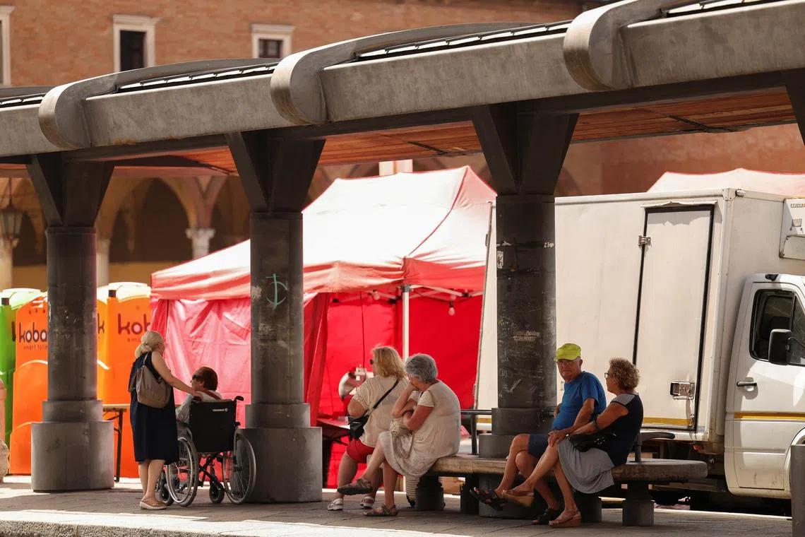 FILE PHOTO: Elderly people take shelter from the sun at a bus station in Forli, Italy, July 19, 2023. REUTERS/Claudia Greco/File Photo