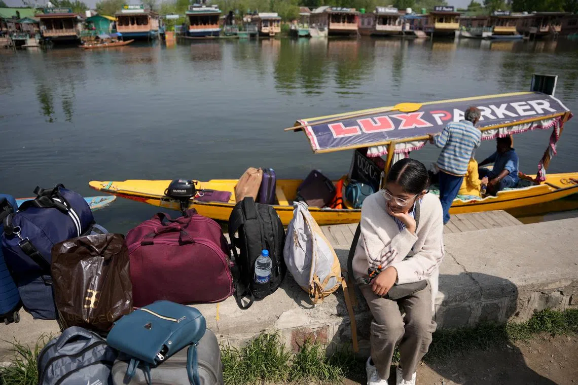 A tourist sits on the banks of Dal Lake with her belongings as she waits for transport to leave for Srinagar airport, following a suspected militant attack near south Kashmir’s scenic Pahalgam, April 23, 2025. REUTERS/Sanna Irshad Mattoo
