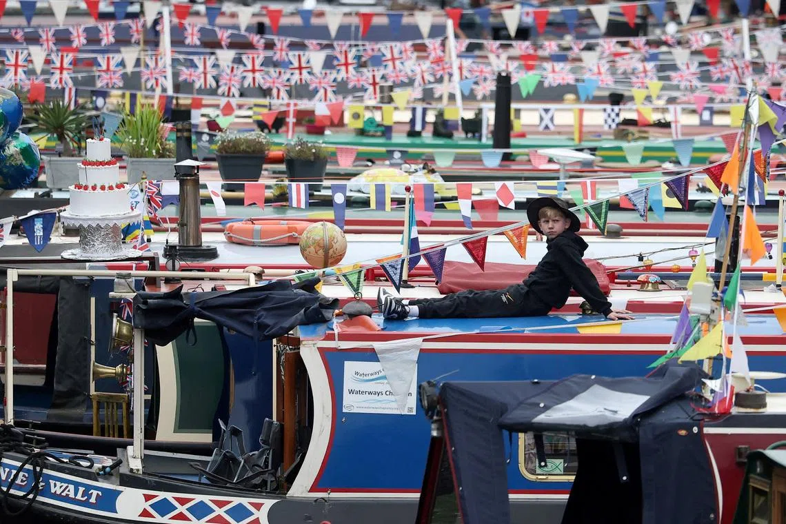 A boy sits atop a narrow boat during the Canalway Cavalcade waterways three-day festival in Little Venice, London, Britain, May 4, 2026. REUTERS/Toby Melville TPX IMAGES OF THE DAY