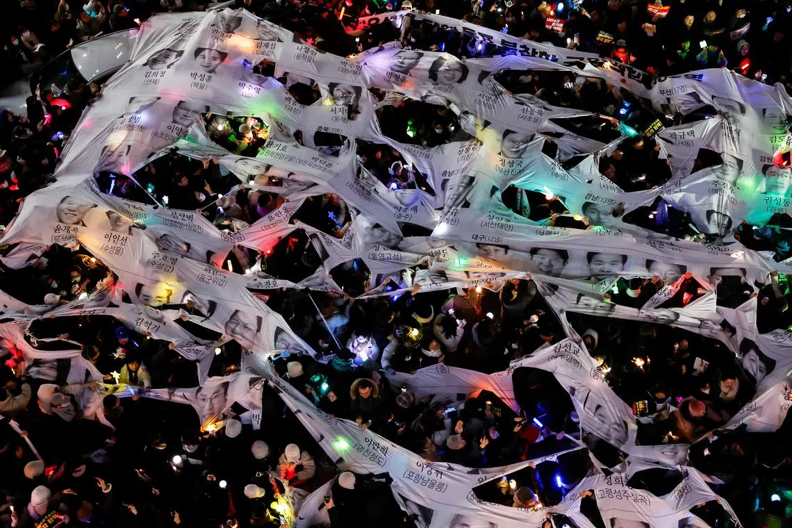 Protesters tearing a banner depicting faces of ruling People Power Party lawmakers during in a rally calling for the impeachment of South Korean President Yoon Suk Yeol, in front of the headquarters of the ruling People Power Party, in Seoul, South Korea, Dec 12, 2024. 