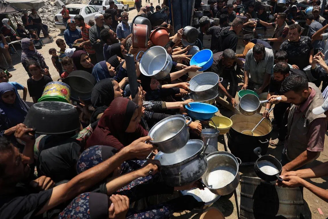 Palestinians gather to receive food from a charity kitchen, amid a hunger crisis, in Gaza City on July 22, 2025.  