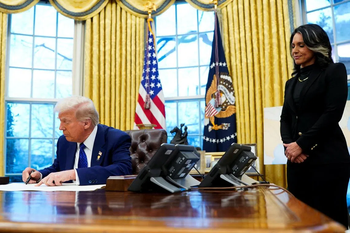 U.S. President Donald Trump signs a document as Tulsi Gabbard  stands by, on the day of her swearing in ceremony as Director of National Intelligence, in the Oval Office at the White House in Washington, D.C., U.S., February 12, 2025. REUTERS/Nathan Howard/File Photo
