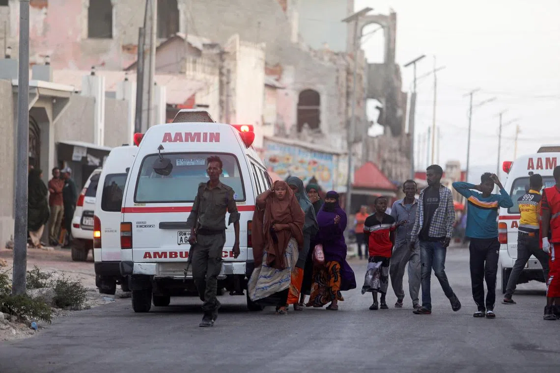 Somali security forces and civilians walk to view the bodies of suspected Al-Shabaab fighters killed at the mayor's office in Mogadishu.