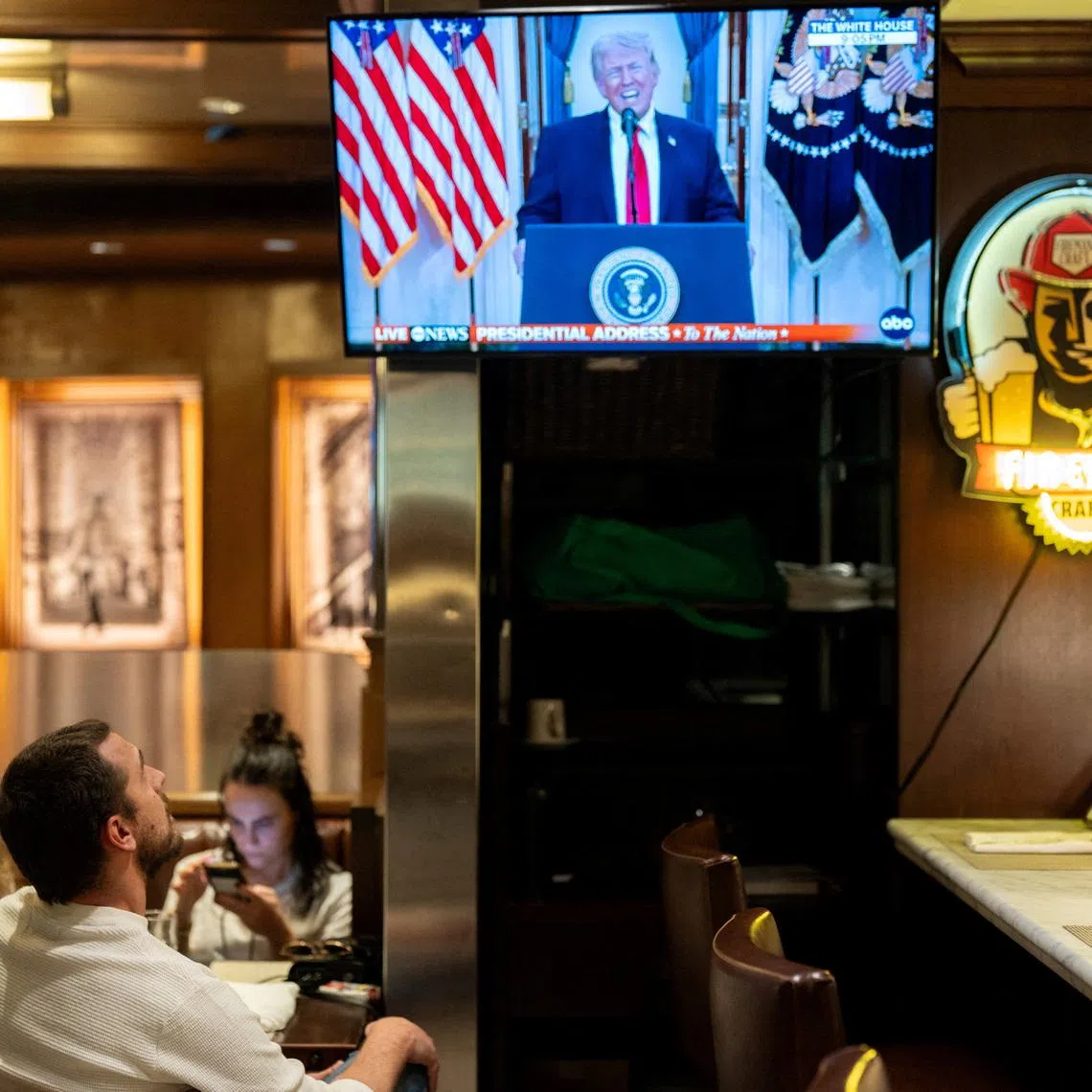 A customer watches U.S. President Donald Trump address the nation on the Iran crisis from the White House in Washington, D.C., on screen at Brooklyn Diner in Times Square, New York, U.S., April 1, 2026. REUTERS/David Dee Delgado