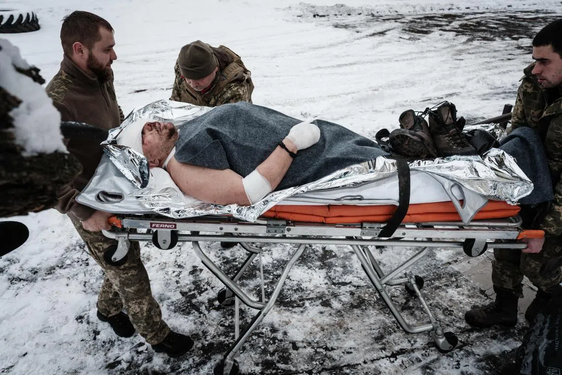 Paramedics transfer an injured Ukrainian serviceman to an ambulance after emergency treatment, in Ukraine's Donetsk region, on Jan 29, 2023.