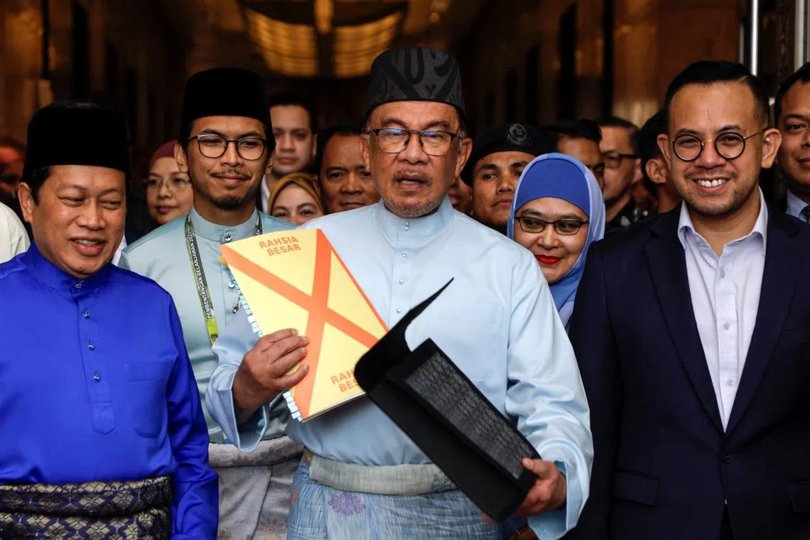 Malaysia's Prime Minister Anwar Ibrahim holds the 2023 Malaysia's budget document at the Finance Ministry building, on Feb 24, 2023.