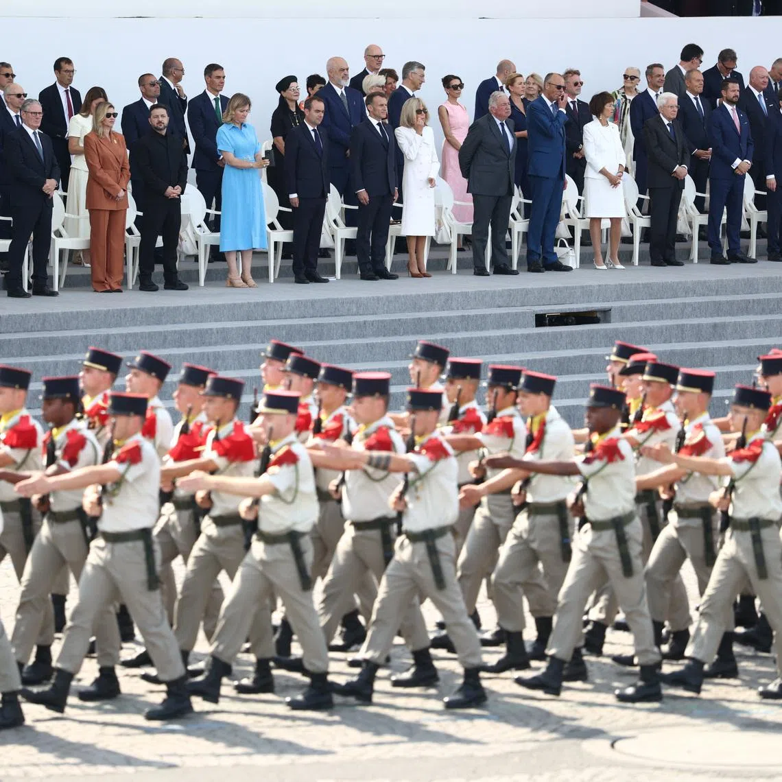 French President Emmanuel Macron, his wife Brigitte Macron, Ukraine's President Volodymyr Zelenskiy and his wife Olena Zelenska, Heads of State and Government of the Coalition of the Willing and members of the French government attend the annual Bastille Day military parade on the Place de la Concorde in Paris, France, July 14, 2026. REUTERS/Tom Nicholson
