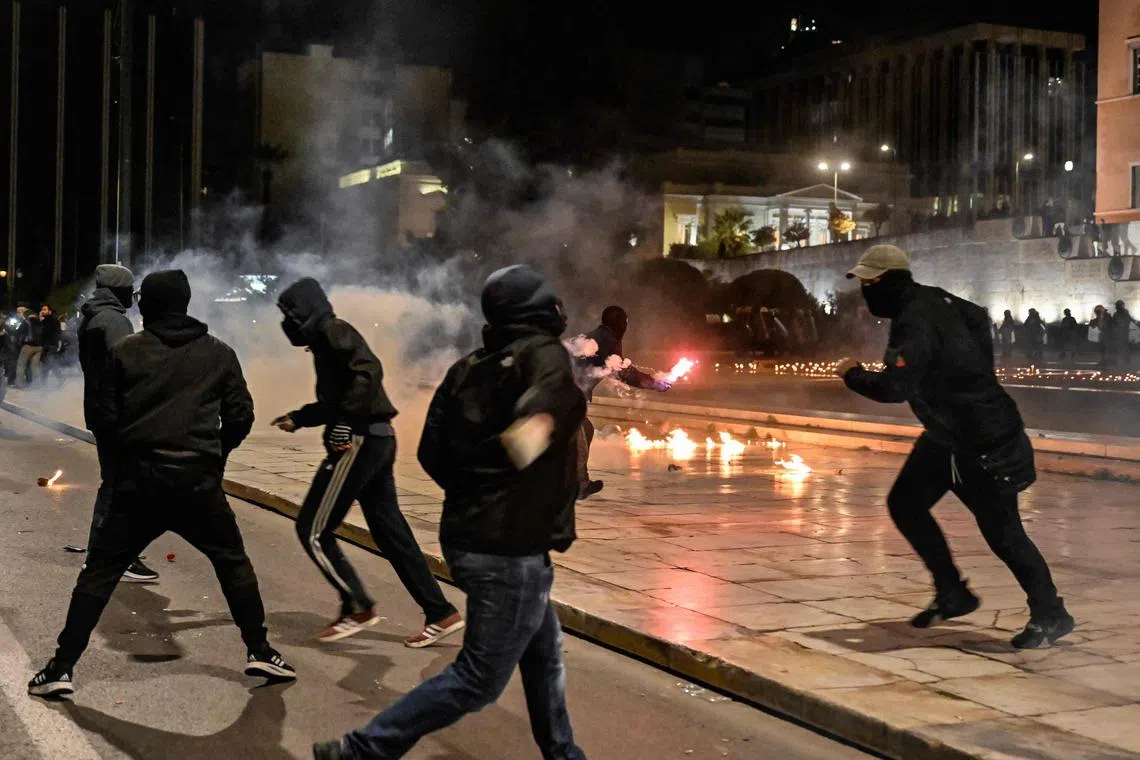 Youths throw molotov cocktails and stones towards police in front of the Greek Parliament in Athens, on March 3, 2023.