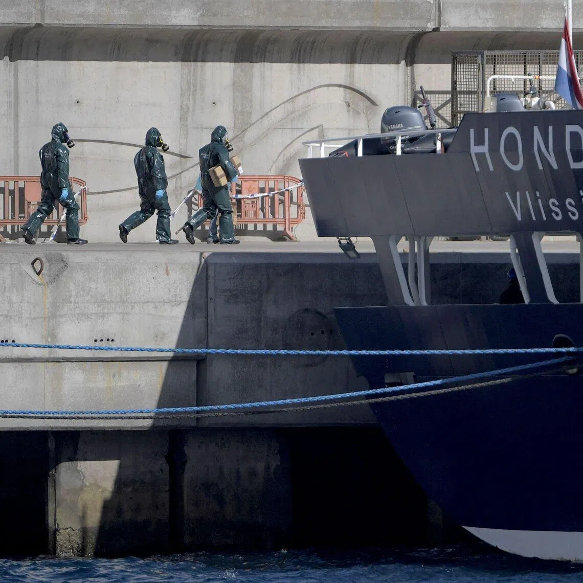 Persons wearing protective suits walk toward the cruise ship MV Hondius docked in the port of Granadilla de Abona in Spain, on May 11.