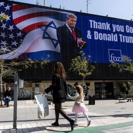 People walk by a billboard commissioned by an evangelical group, which displays a picture of US President Donald Trump, in Tel Aviv, Israel, on March 12.
