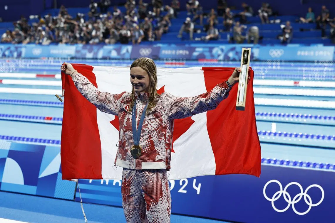 Paris 2024 Olympics - Swimming - Women's 200m Butterfly Victory Ceremony - Paris La Defense Arena, Nanterre, France - August 01, 2024. Gold medallist Summer McIntosh of Canada holds the flag of Canada. REUTERS/Clodagh Kilcoyne