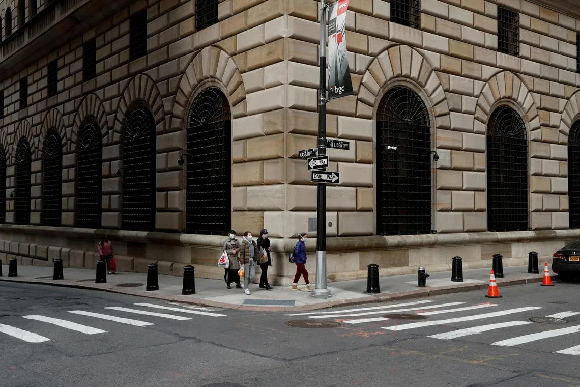 People walk wearing masks outside The Federal Reserve Bank of New York in New York City, U.S., March 18, 2020. REUTERS/Lucas Jackson/File Photo
