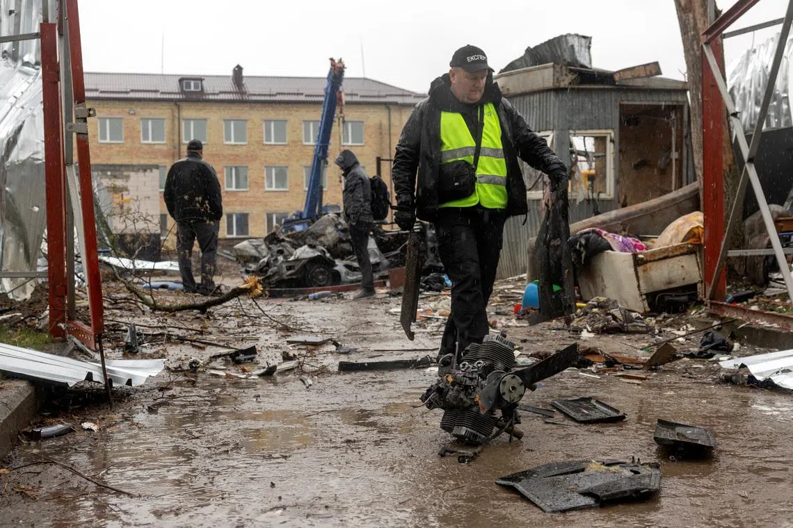 An investigator collects debris of a Russian drone at the impact site in a residential neighborhood, amid Russia's attack on Ukraine, in Vyshneve, outside Kyiv, Ukraine, April 3, 2026. REUTERS/Thomas Peter
