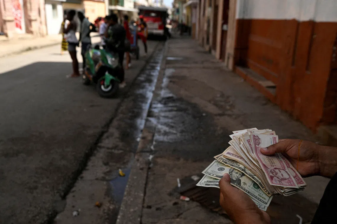 A person holds US dollars and Cuban pesos in downtown Havana, Cuba in August.